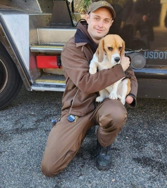 the UPS driver is holding a sad dog in his arms