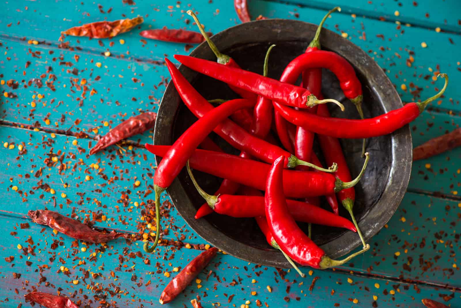 vintage bowl with red pepers over dried chili in background on table