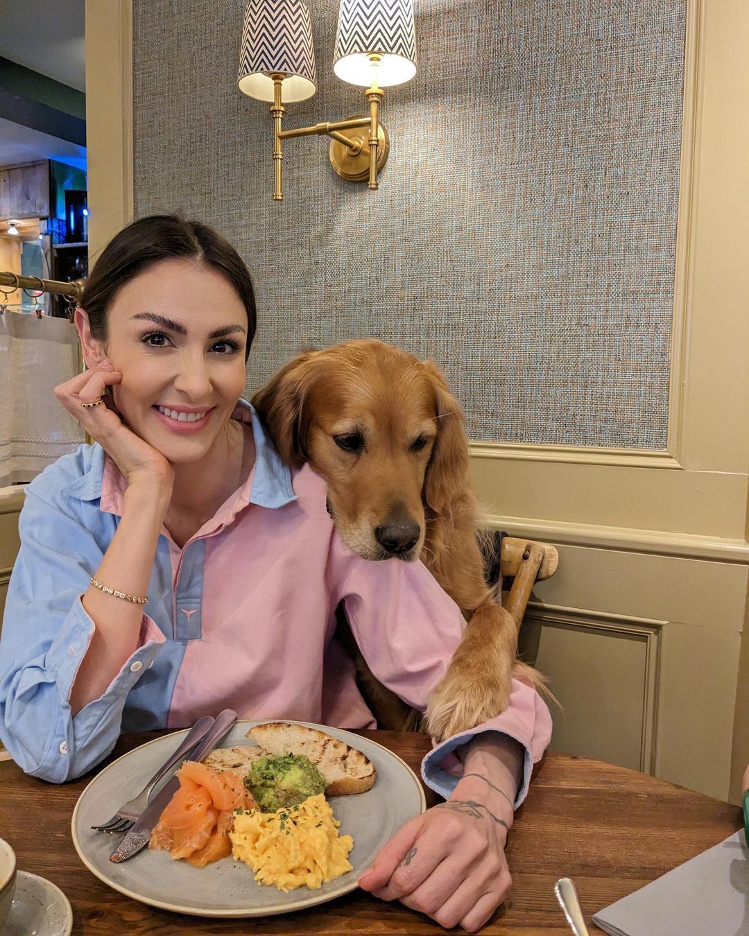 woman and golden retriever sitting at table