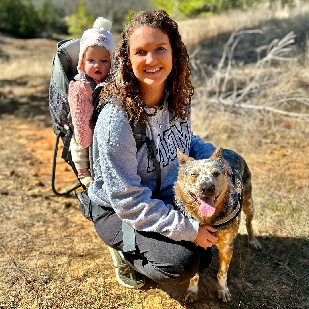 woman carrying a baby on her backand with her dog