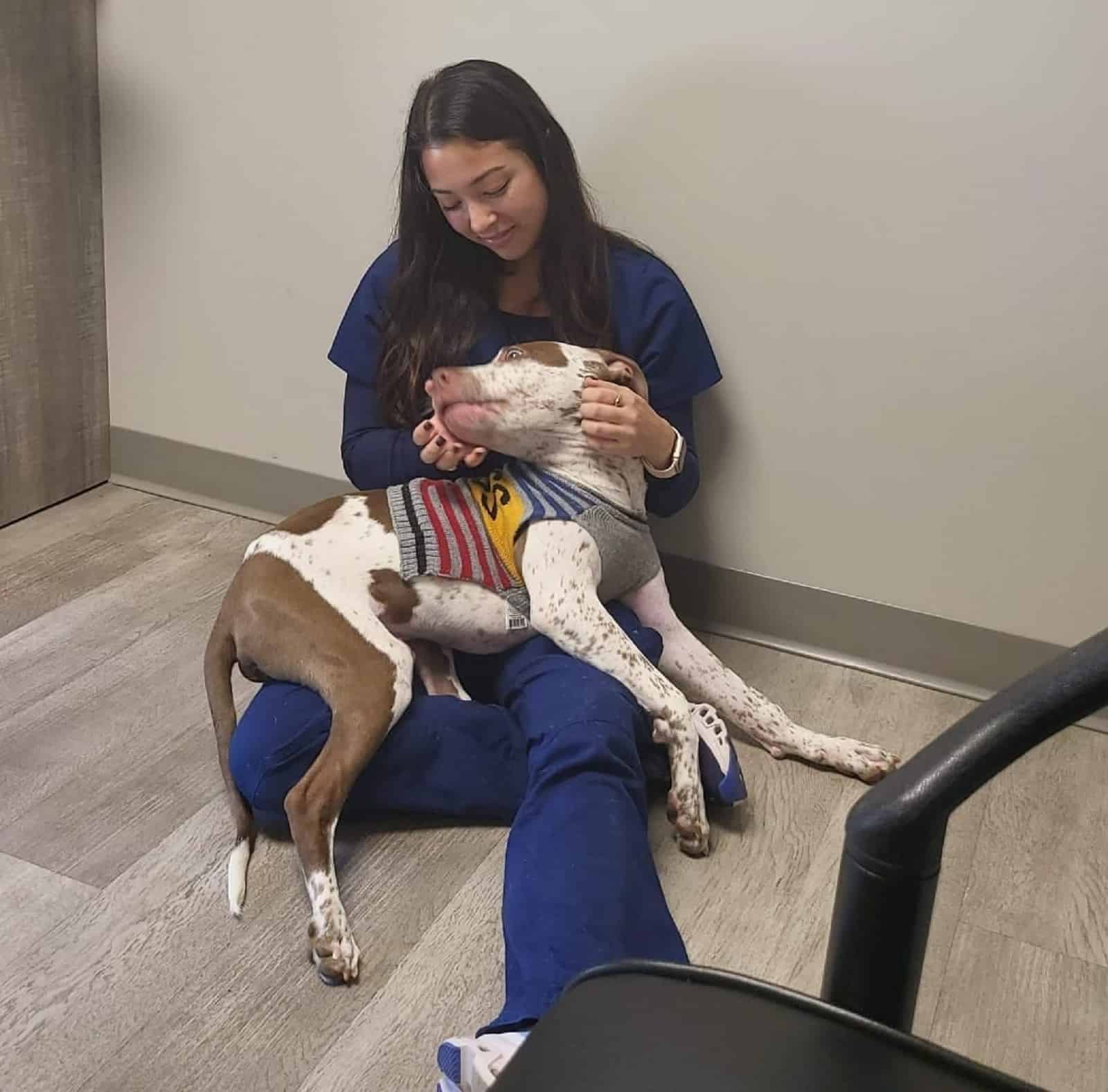 woman cuddling with a dog on the floor