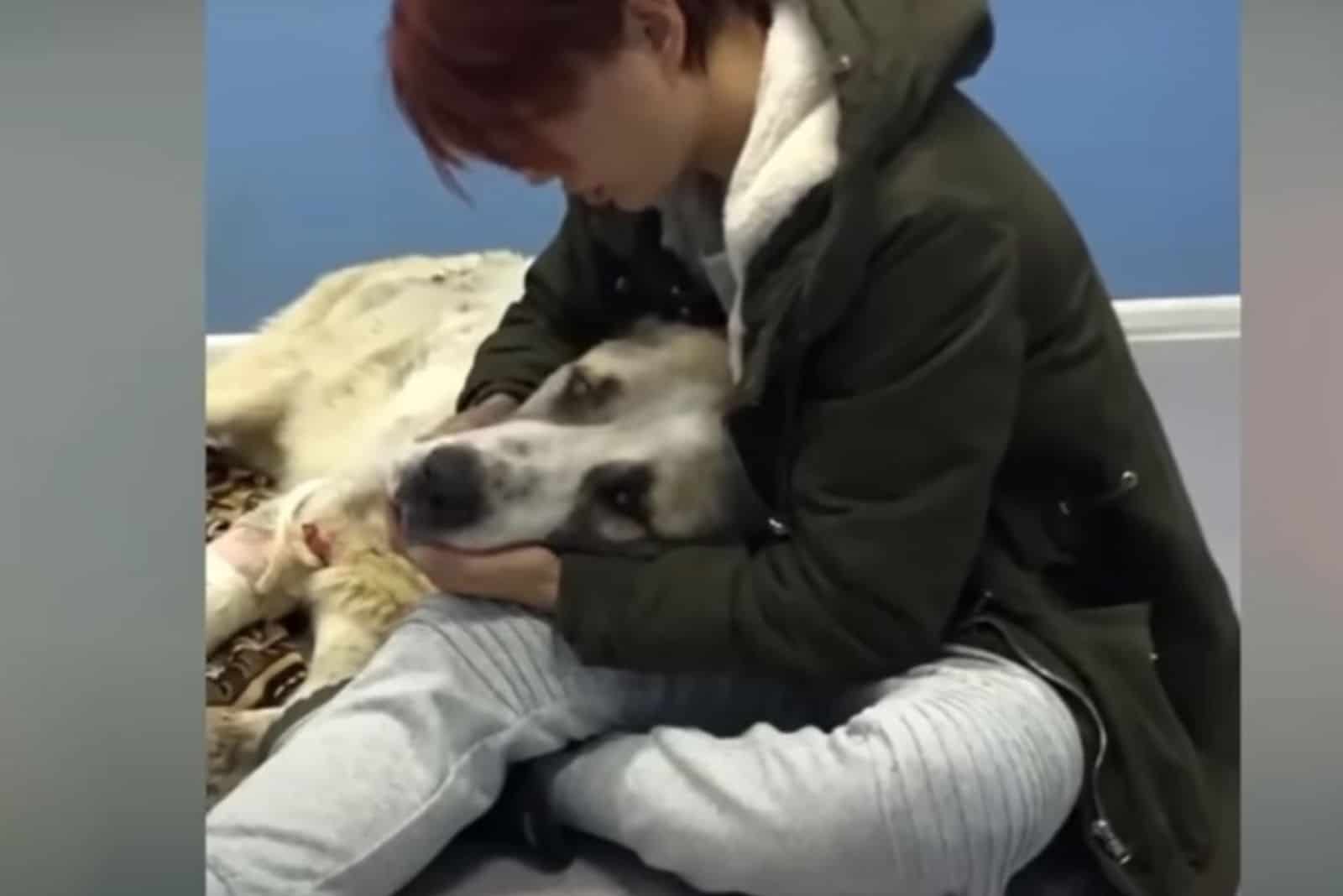 woman embracing a dog lying on the floor