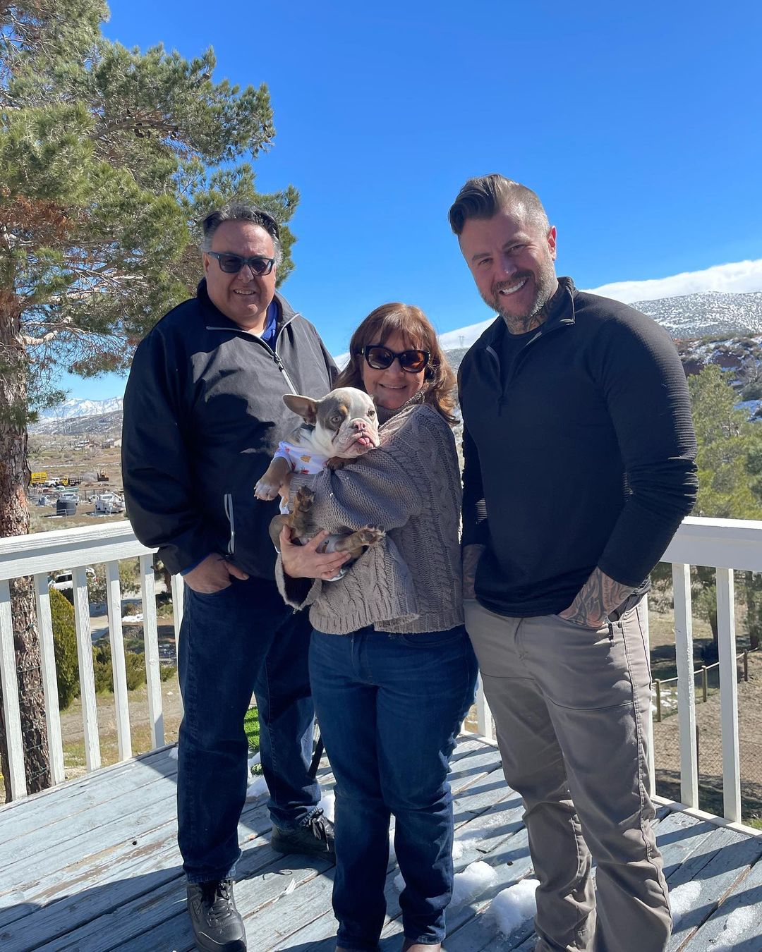 woman holding a dog and standing next to two men