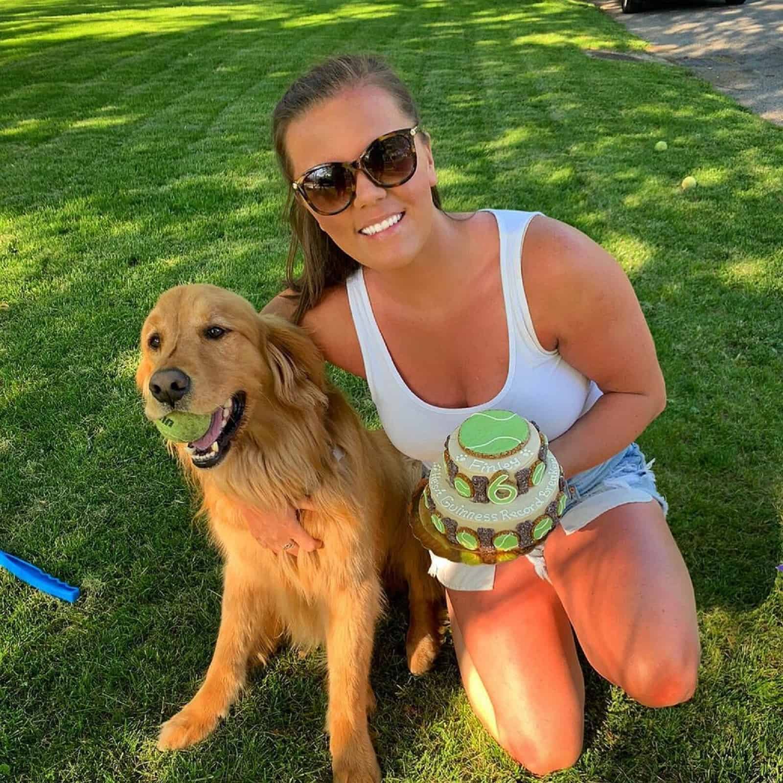 woman hugging dog holding tennis mouth in his mouth