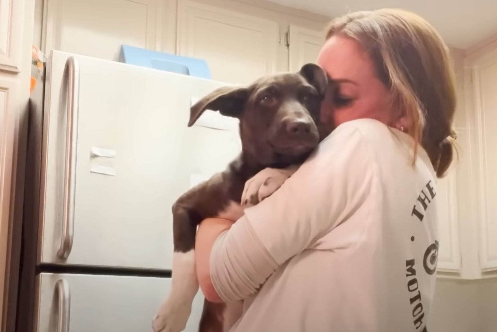 woman kissing dog in arms