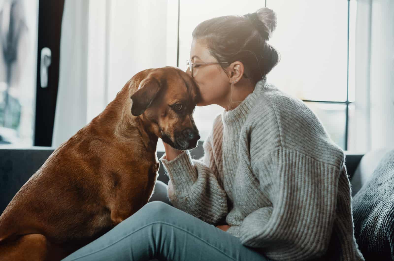 woman kissing dog on head