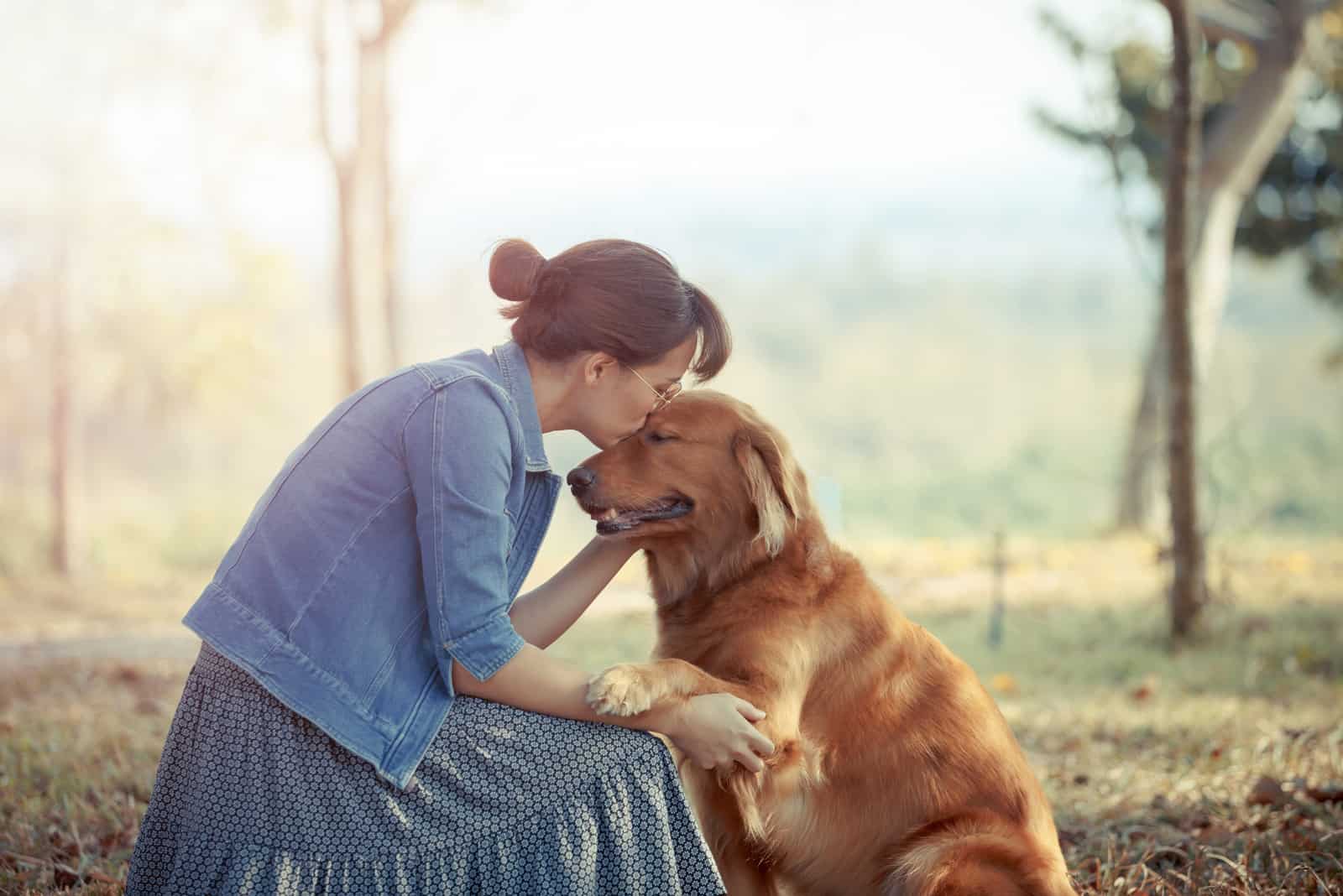 woman kissing golden retriever in the head