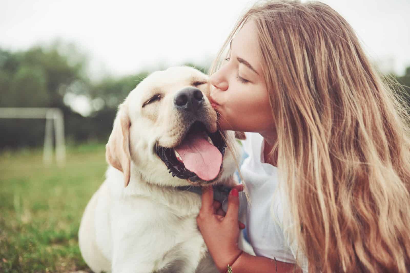 woman kissing her dog in the park