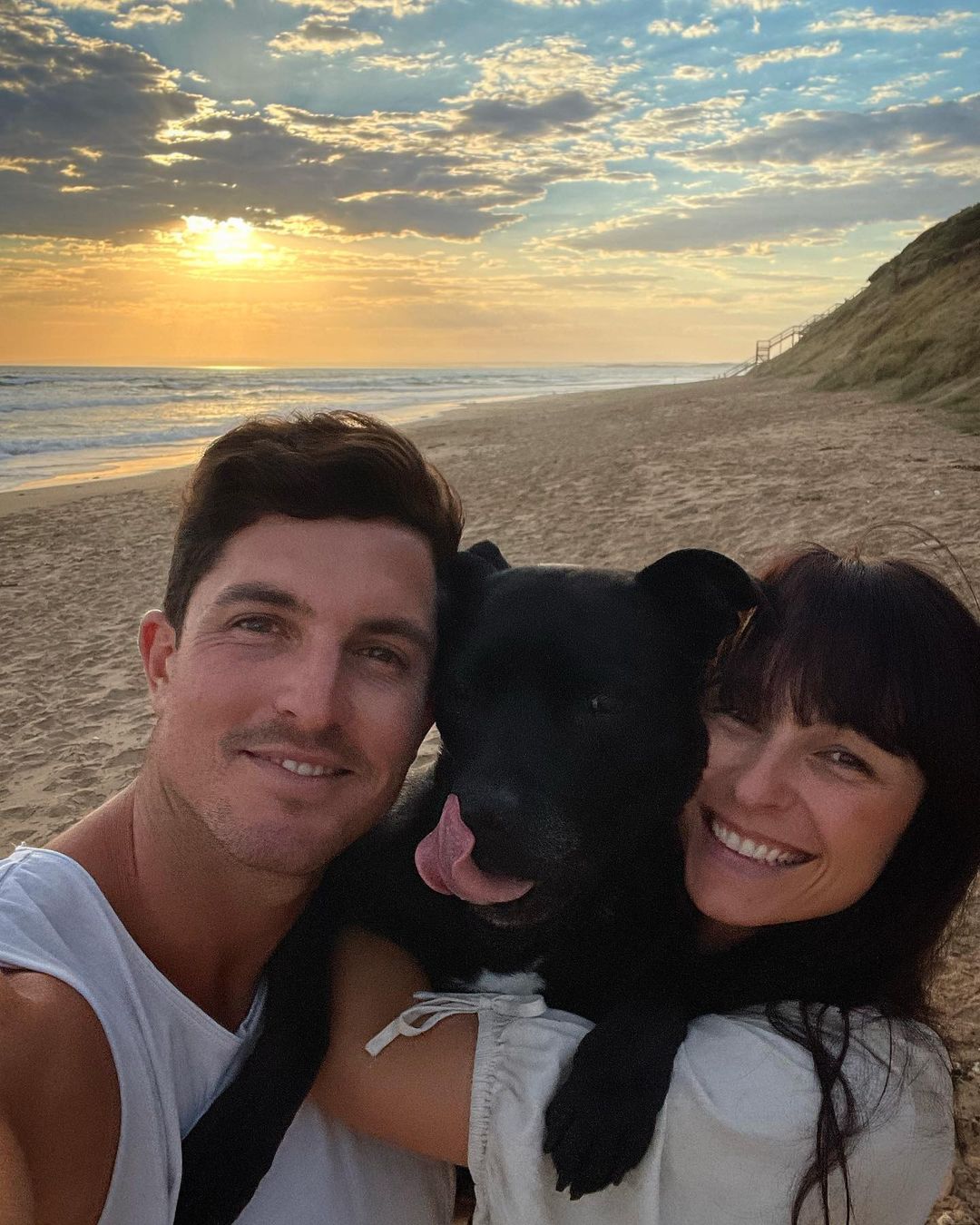 woman, man and a dog at the beach at sunset