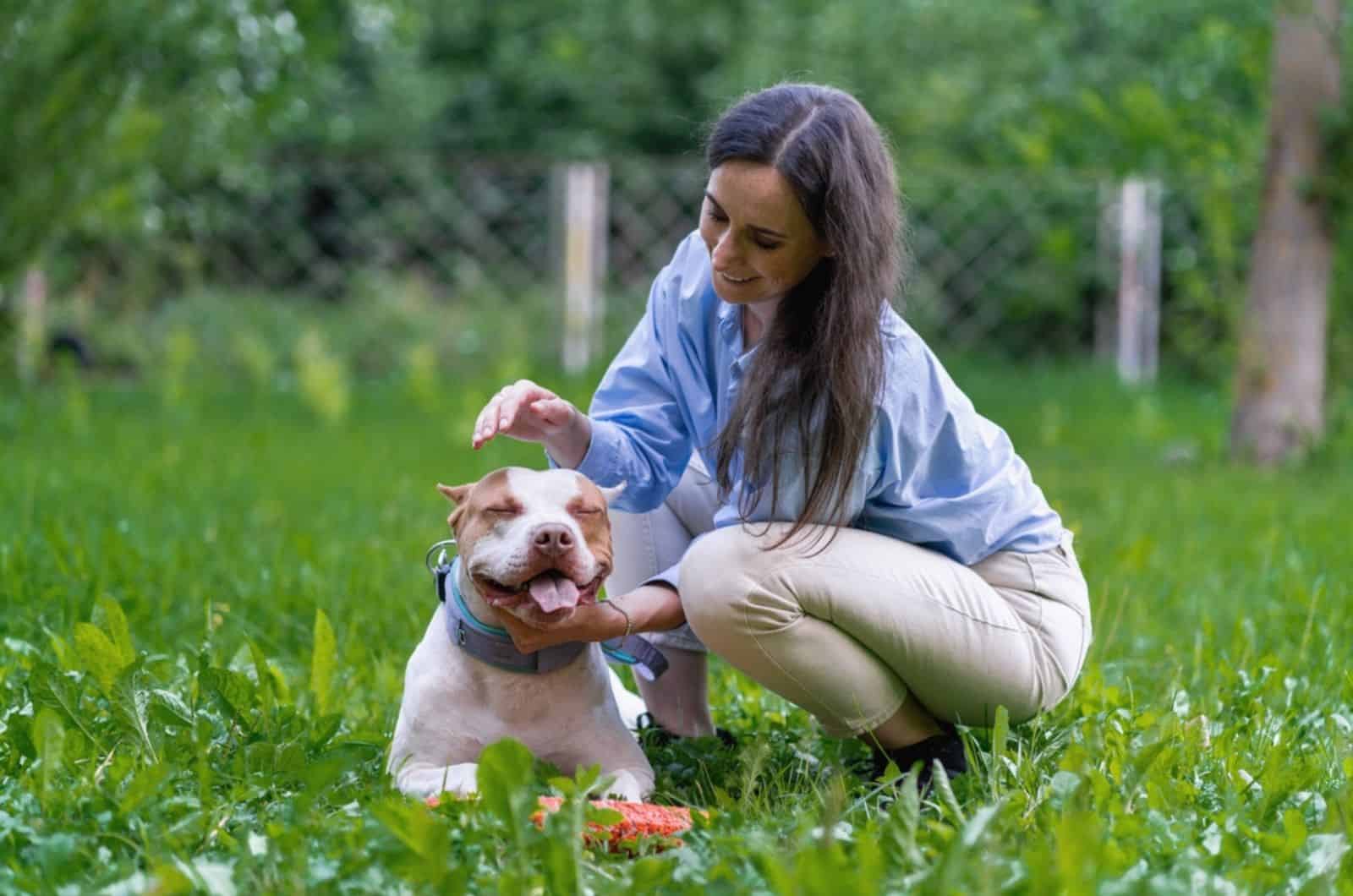 woman petting his pitbull in the yard