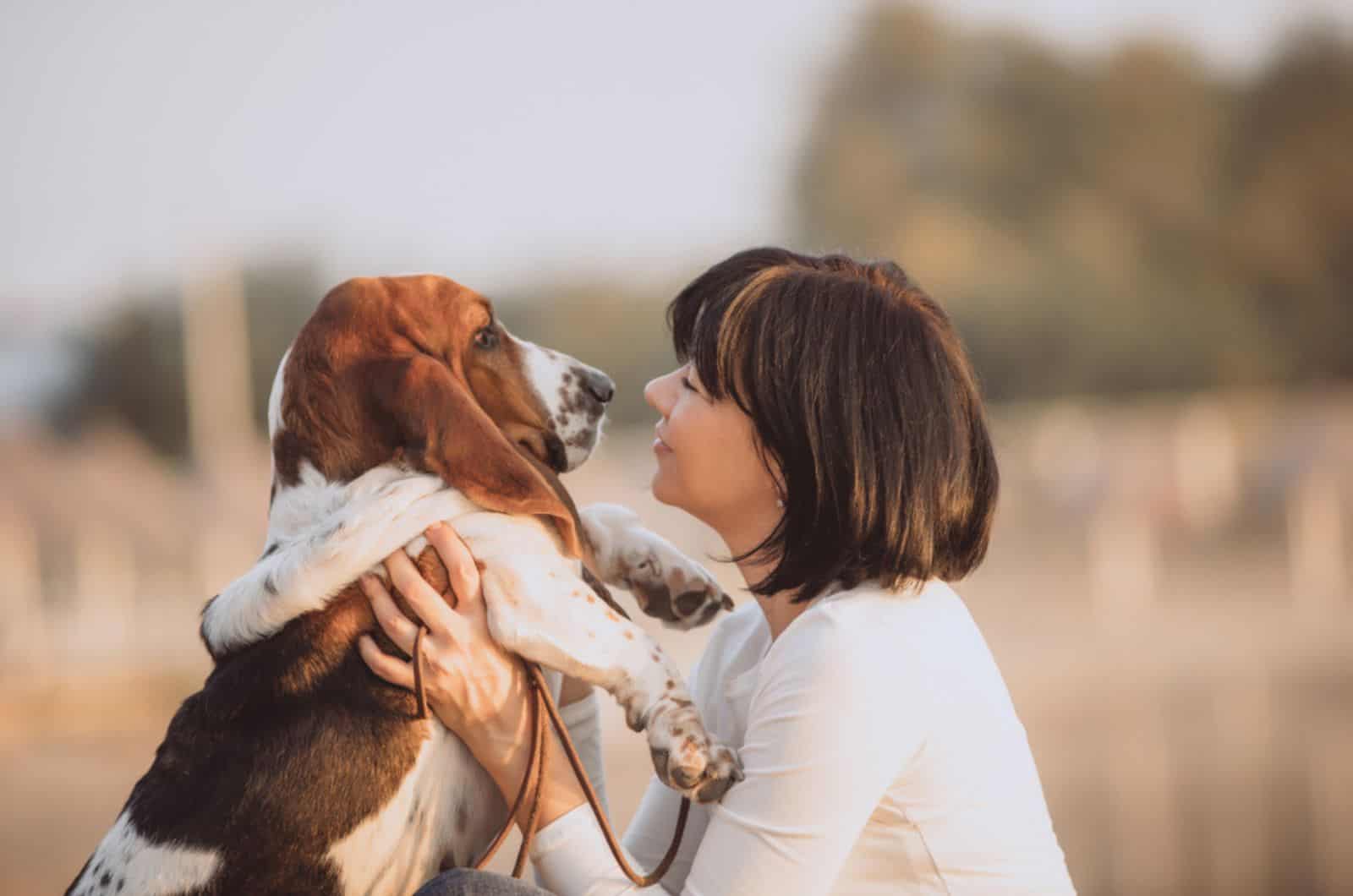 woman playing with her dog basset hound in nature