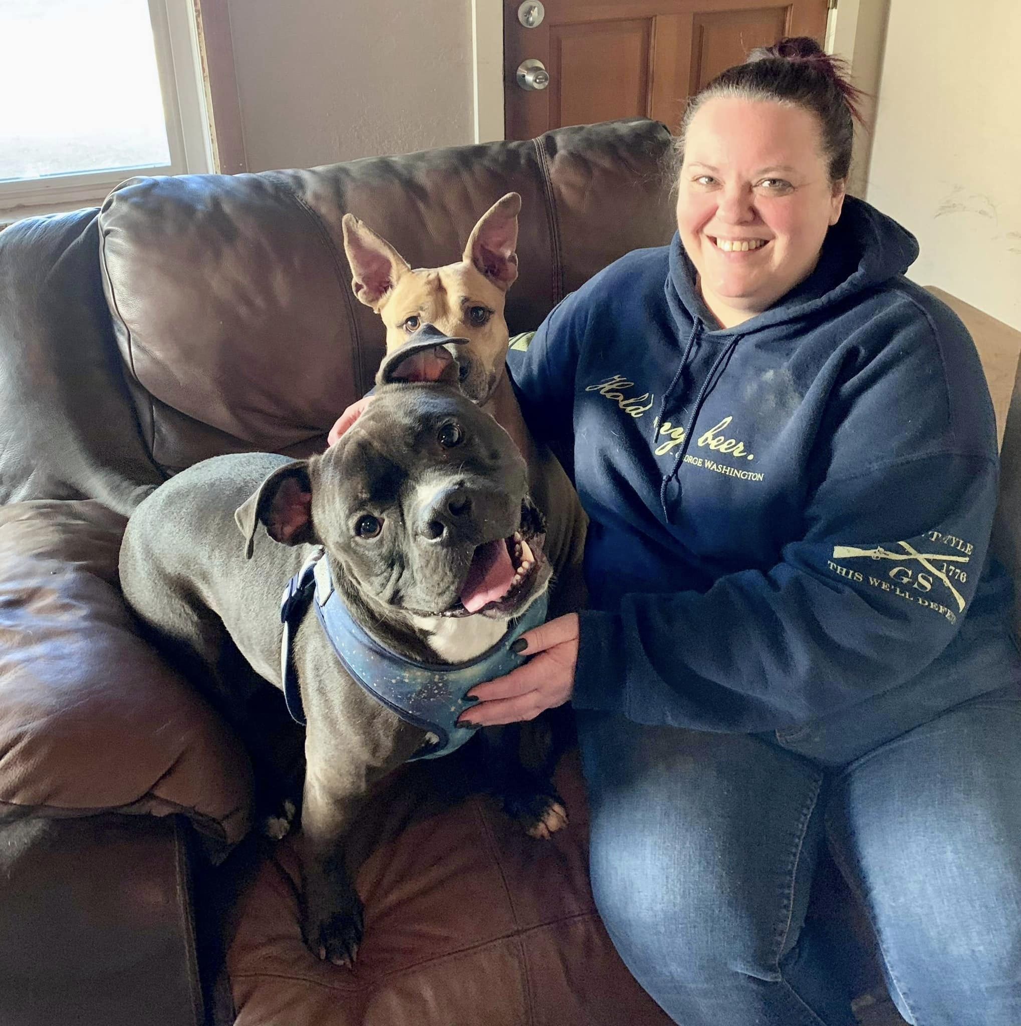 woman sitting on a couch with two dogs