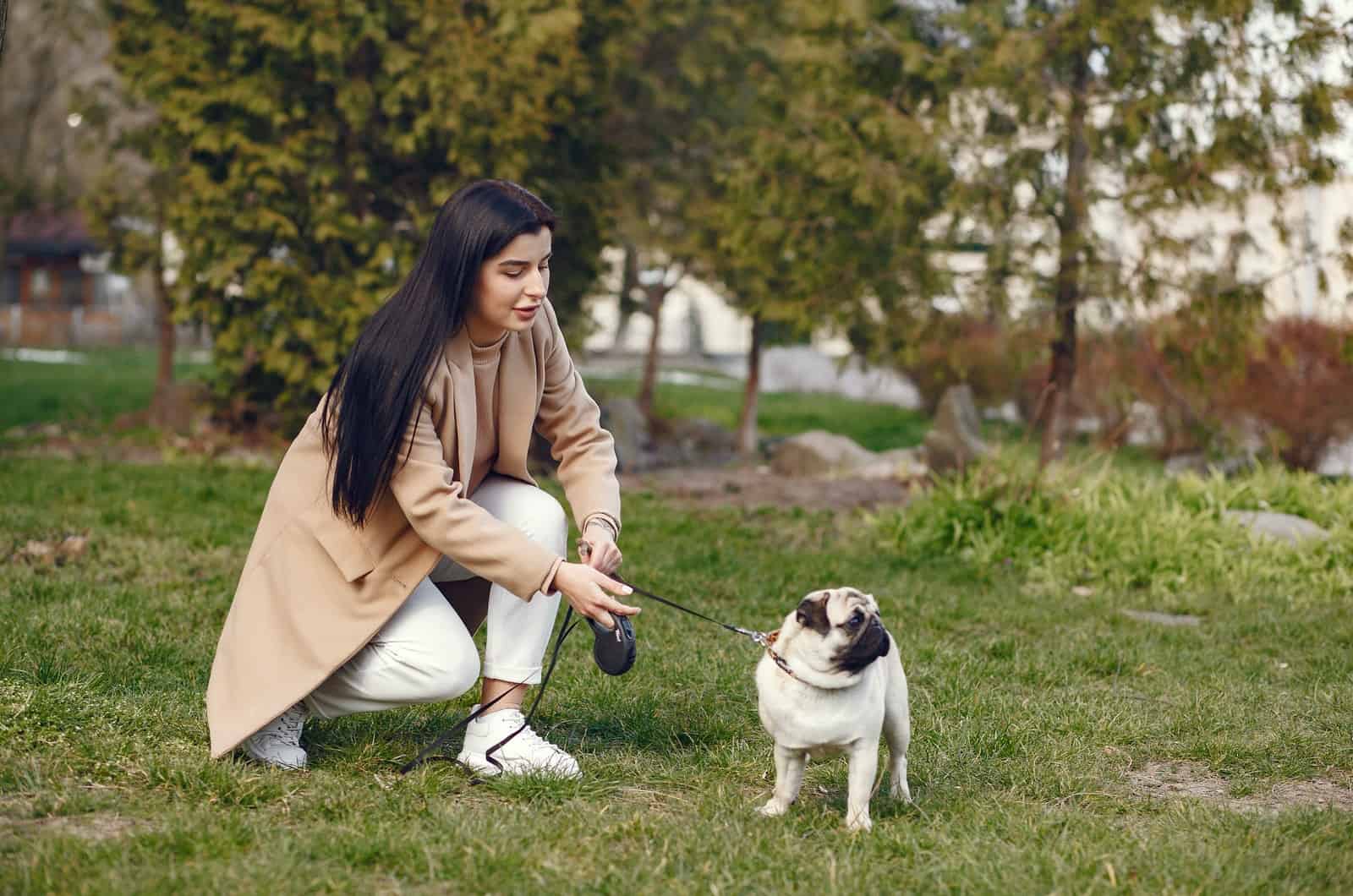 woman standing next to her dog in park