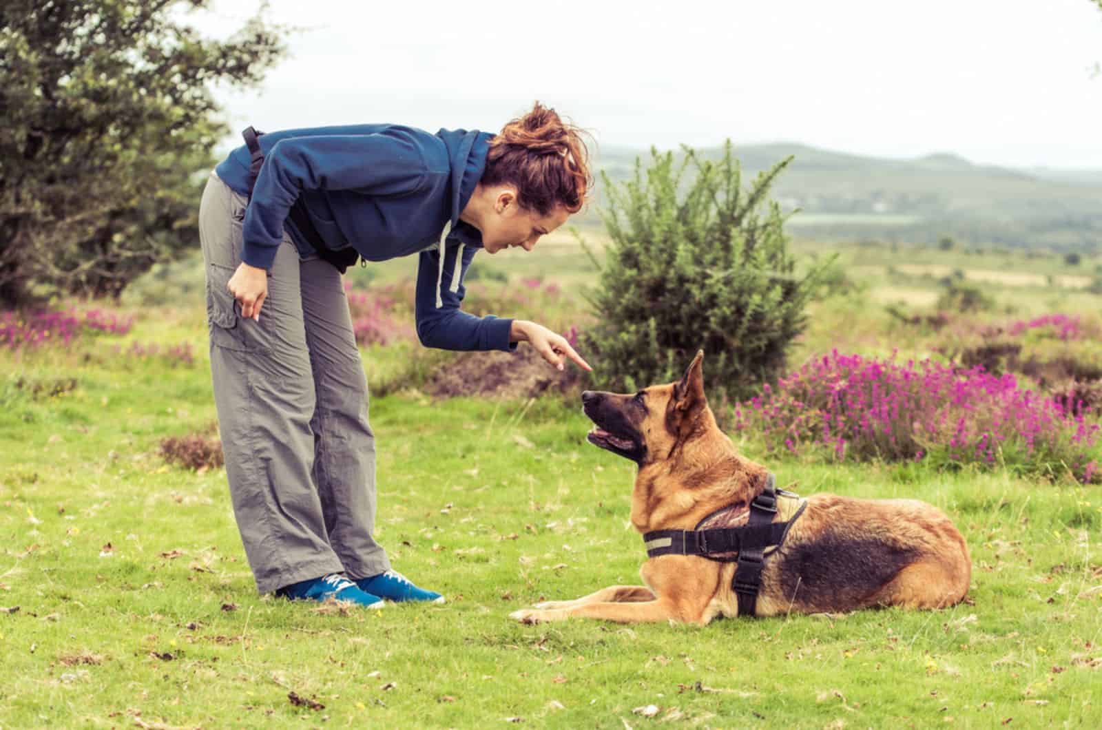 woman tell dog to sit during training