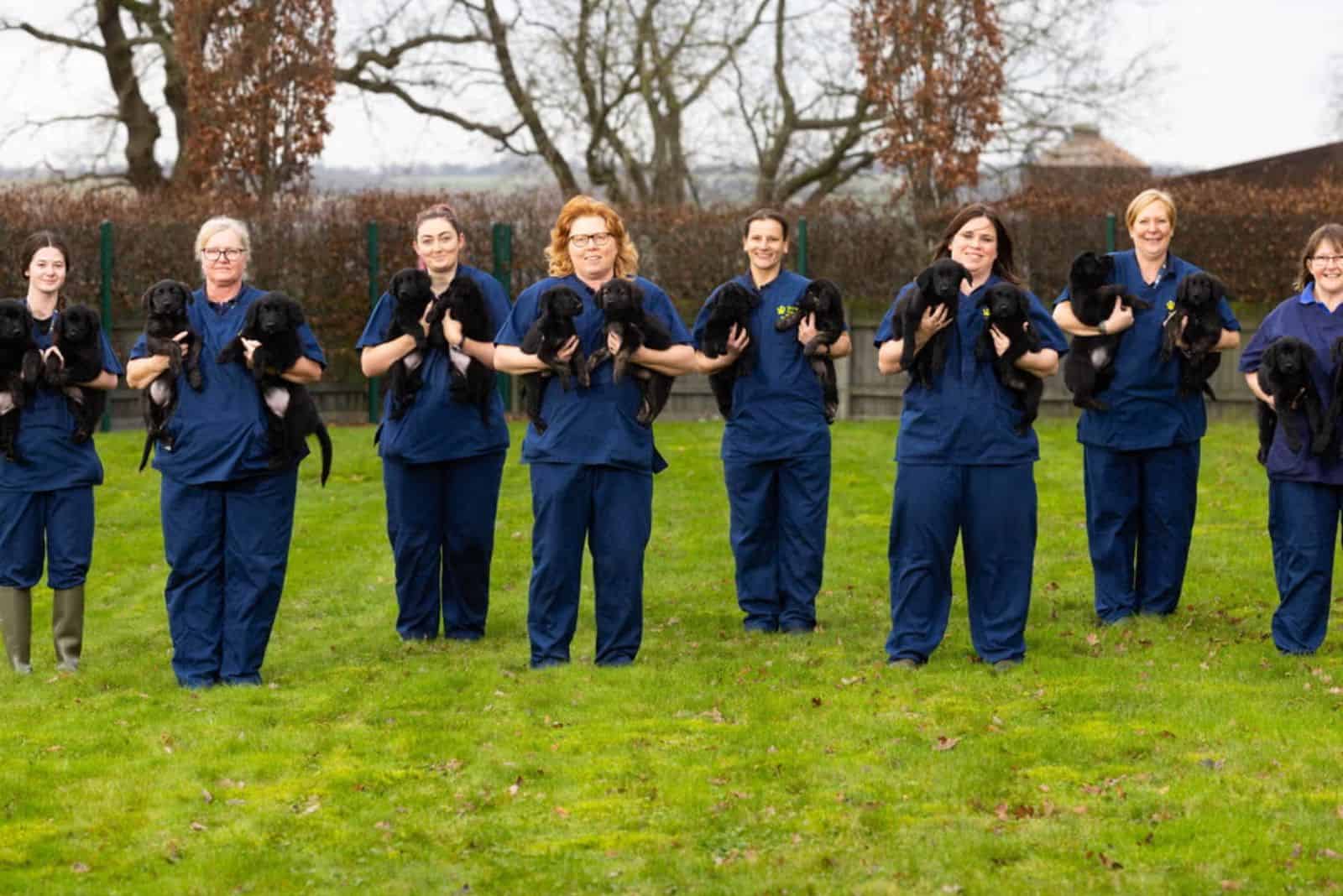 women holding puppies in arms on a lawn