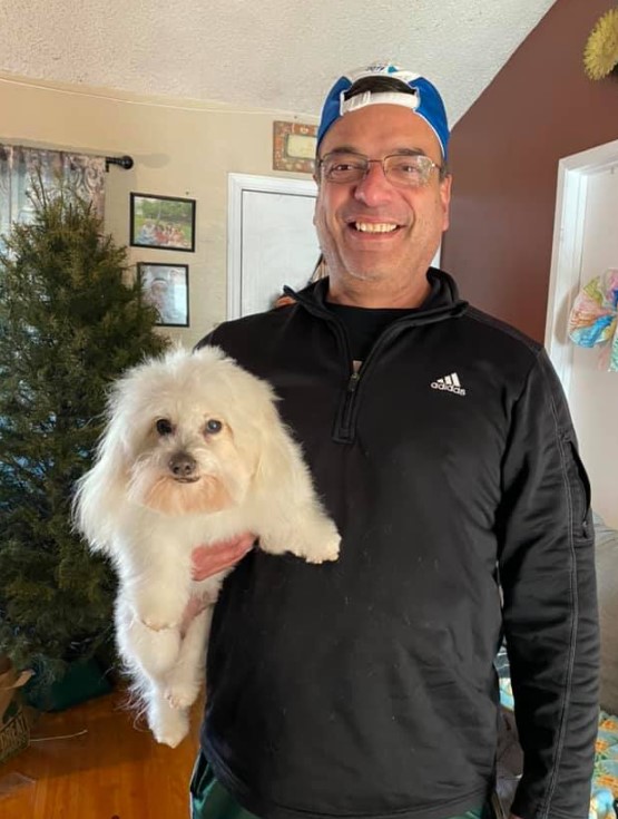 a smiling man holds a dog in his arms