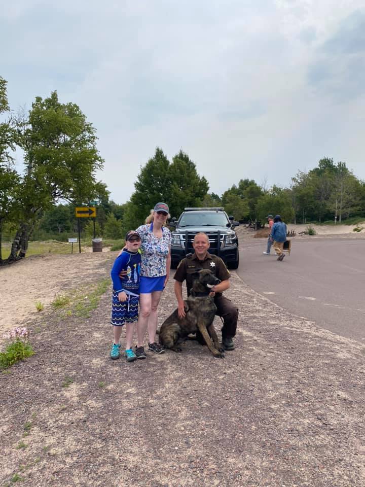 K9 dog posing with police officer, woman and a kid