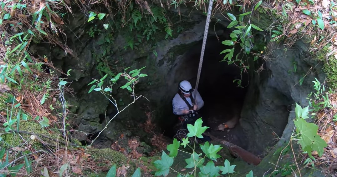 man on a rope going into the cave