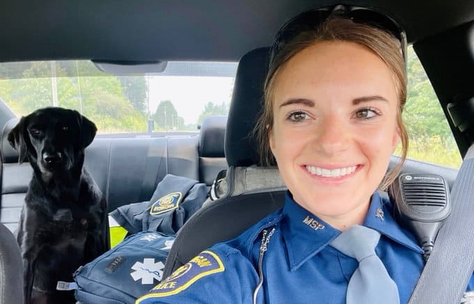 state trooper and a dog sitting in a car