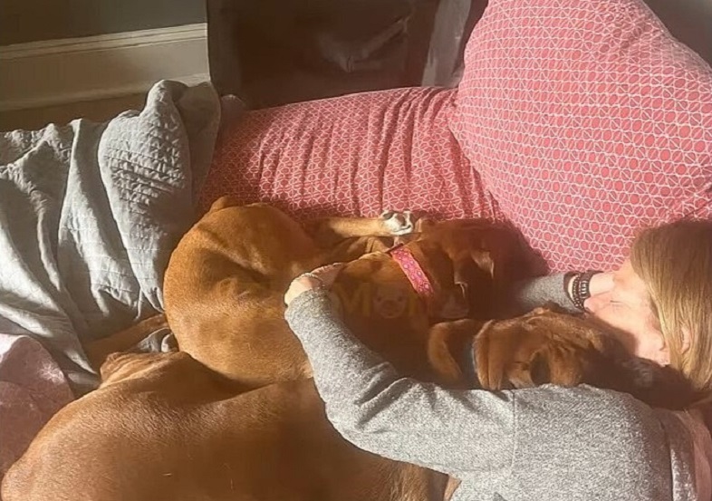 woman cuddling with two dogs