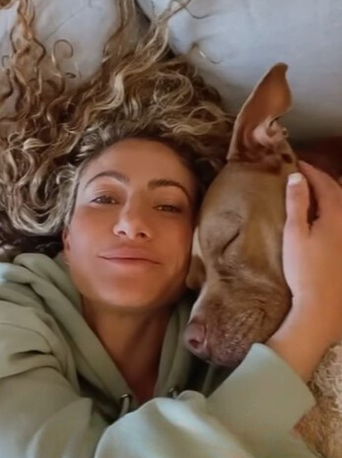 woman with curly hair in hug with dog