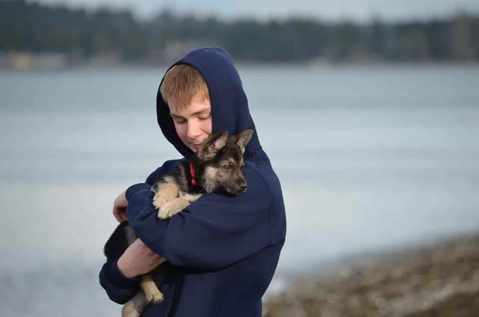 young man holding german shepherd puppy in his arms