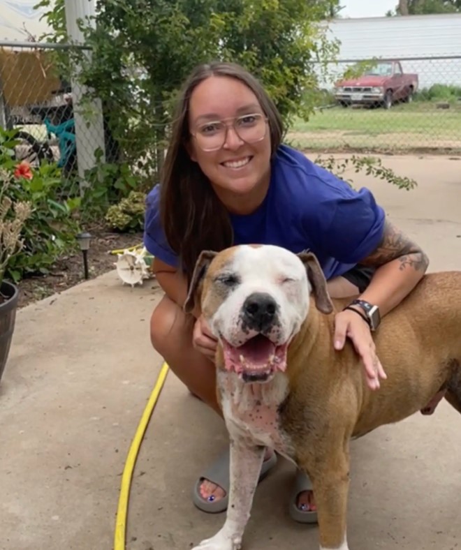 a smiling woman takes a picture with her dog