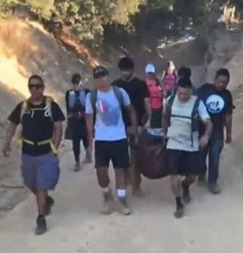 hikers carrying a German shepherd