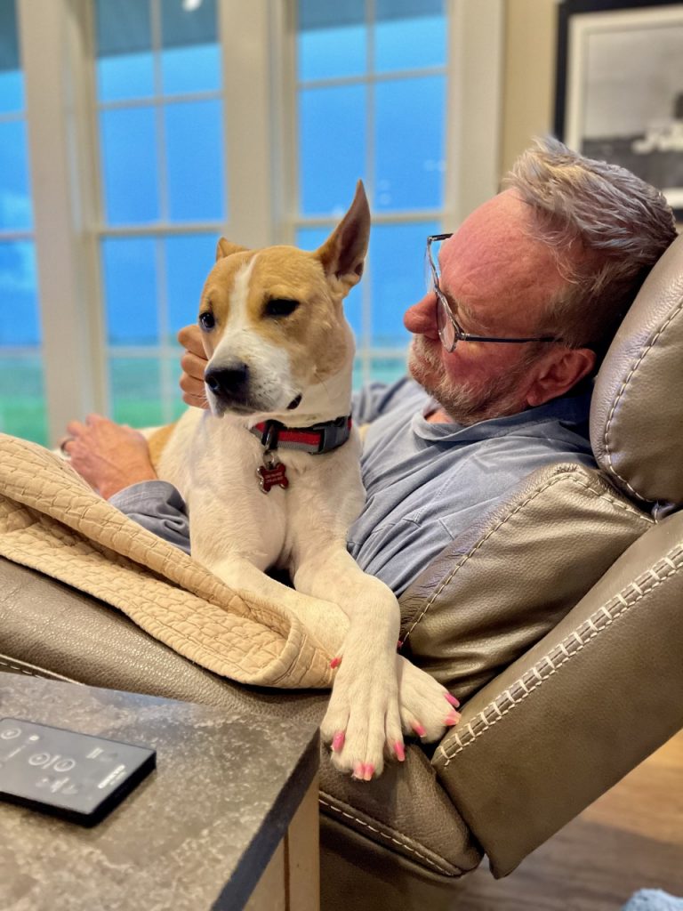 man laying on the chair with his dog