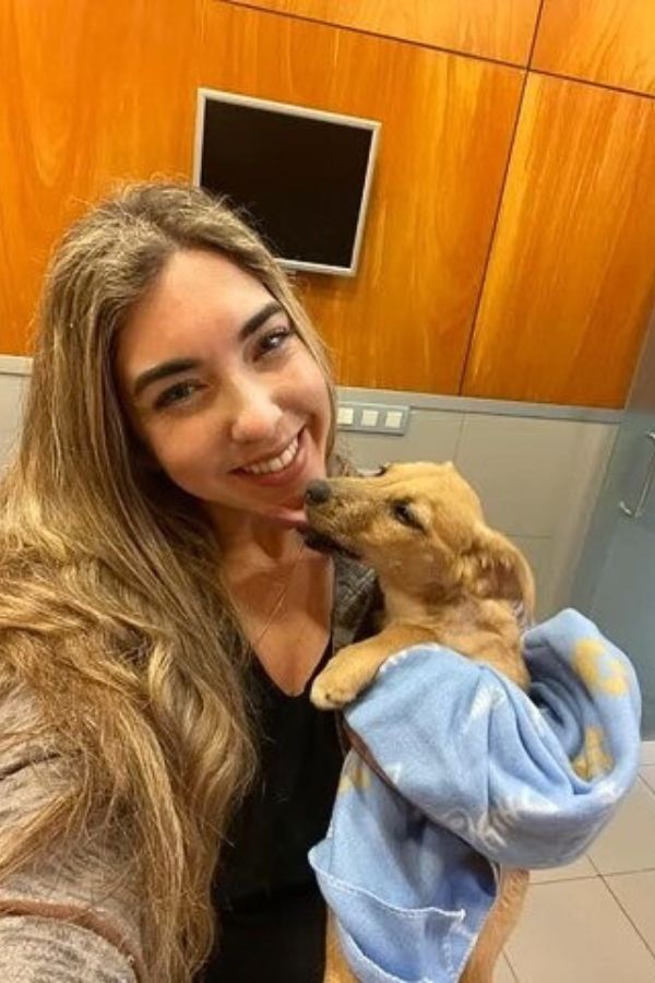 smiling young girl holding a dog in a blanket