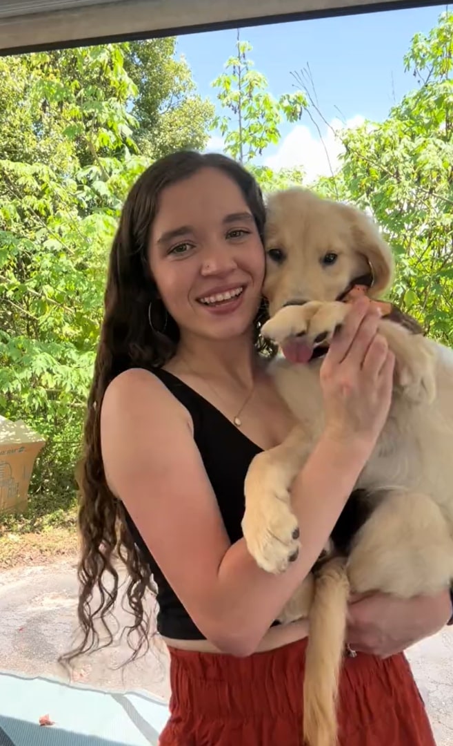 a girl with long black hair holds a dog in her arms