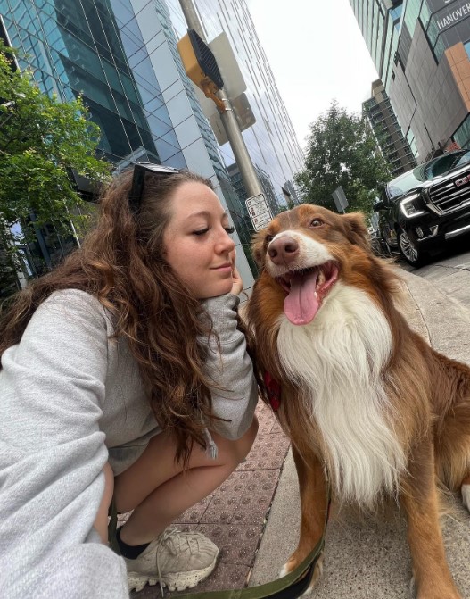 a woman takes a picture with her dog on the street