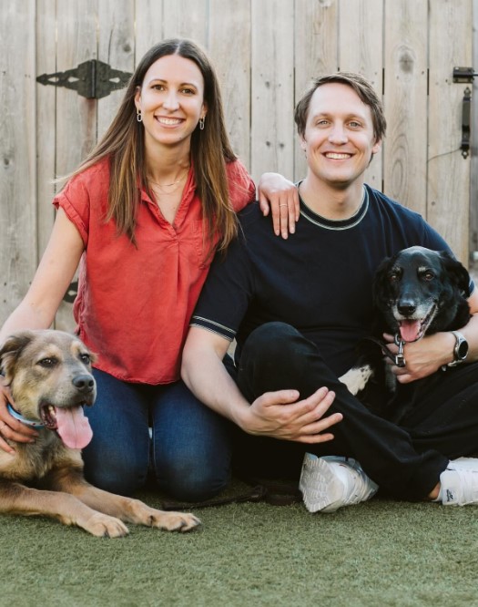 smiling man and woman taking pictures with dogs