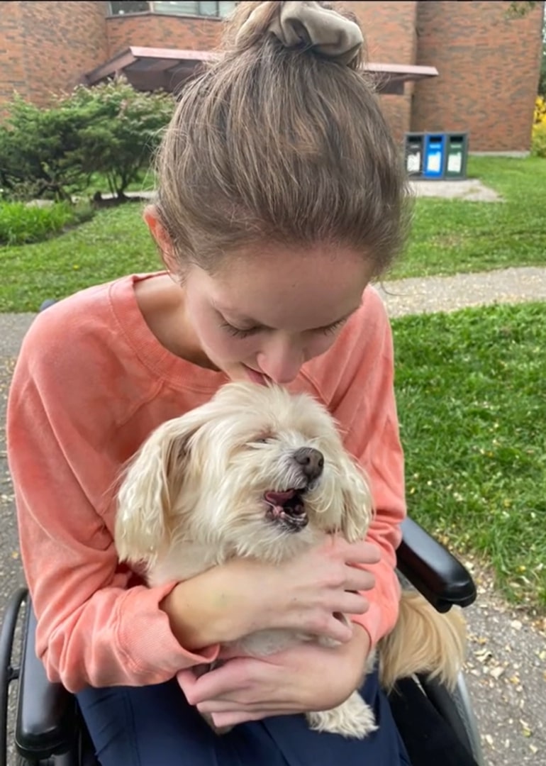 the girl is holding a blind dog in her arms