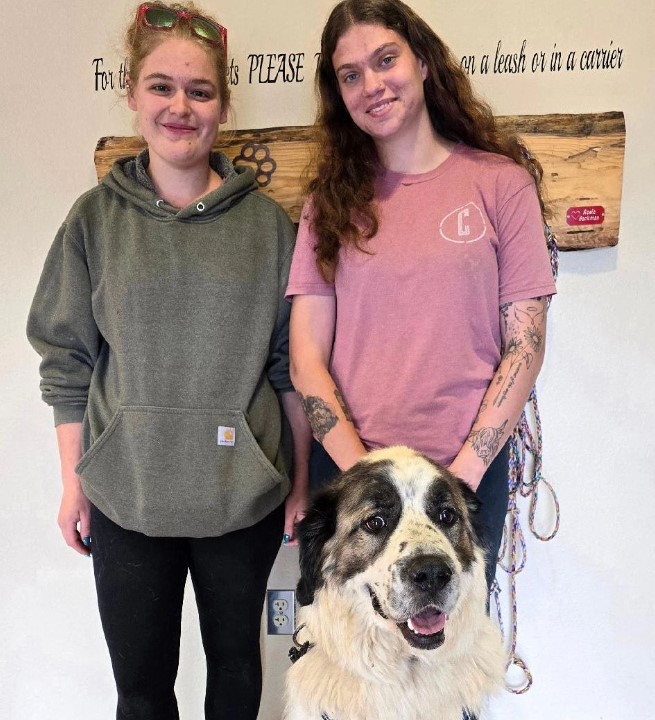 two girls take a picture with a dog